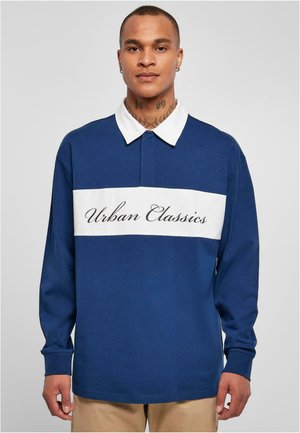 Granatowa koszula polo z długim rękawem z białym poziomym paskiem z napisem „Urban Classics”. Wyraźny kontrastujący kołnierzyk i luźny fason.