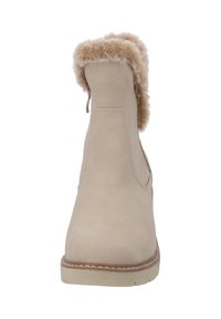 Beige enkellaars met een gladde suède afwerking, nepbont rand aan de bovenkant, ronde neus en een contrasterende zool met stikseldetails.