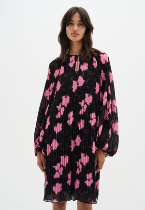 Schwarzes, plissiertes Kleid mit großen rosa und dunkelbraunen Blumendrucken, langen Ärmeln und einem kleinen Schlüsselloch-Ausschnitt.