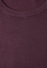 Gros plan d'un col de pull en tricot violet foncé avec un détail de col côtelé et une texture de couture délicate.