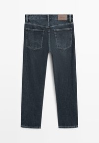 Tmavě modré džíny z denimu se stehnem rovného střihu, dvěma zadními kapsami a koženou štítkem na pásku. Textura je hladká s mírným vyblednutím.