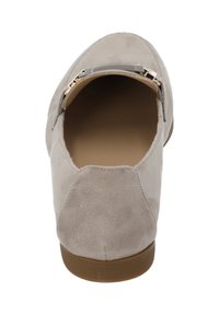 Beige suede instapper met een ronde neus, tan rubberen zool en een decoratieve goudkleurige hardwareaccent op de bovenkant.