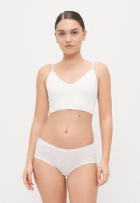 White cotton bralette with thin straps and a v-neckline, paired with matching white hipster briefs, featuring a smooth, stretchy texture.
