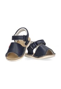 Sandalias de cuero azul marino con diseño de punta abierta, correa de Velcro, suela beige y detalle de costura blanca. Construcción ligera.