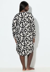 Abito a maniche lunghe con motivo foglia bianco e nero, realizzato in tessuto morbido, con spacchi laterali e scollatura rotonda.