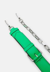 Vihreä nahkavyö, jossa on sileä pinta, hopeiset metalliketjun lenkit ja varusteet, sekä vinoleikkaus toisessa päässä.