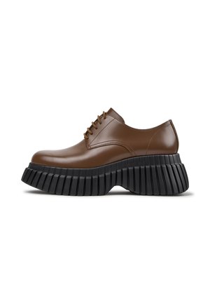 Brown leather lace-up shoe with a thick, ridged black platform sole, shown in side view on a white background.