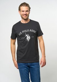 Sort bomulds t-shirt med et hvidt "U.S. Polo Assn." logo og grafik af en polospiller, rund halsudskæring, korte ærmer og en afslappet pasform.