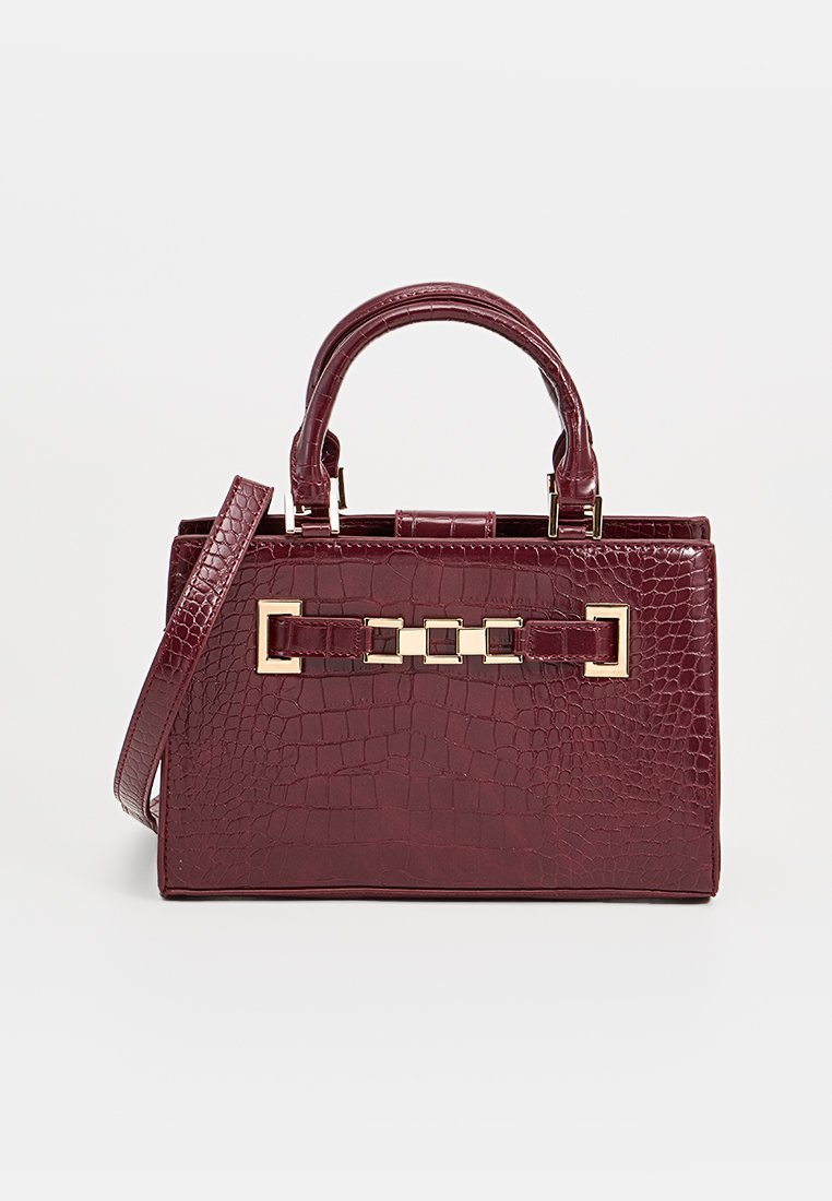 Sac à main en simili cuir bordeaux avec un motif crocodile texturé, des accents en métal doré et deux poignées supérieures. Bandoulière détachable incluse.
