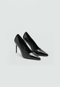 Scarpe con tacco alto in vernice nera, design a punta e tacchi a stiletto sottili. Texture liscia, stile minimalista e senza ferramenta visibile.
