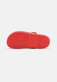 Red rubber sole with textured zigzag tread pattern. Features a strap with multicolored accents and logo embossed on the side.