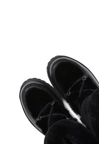 Botines negros con textura suave, parte superior de cuero, puntera redondeada y cierre con cordones con detalles de herrajes metálicos.