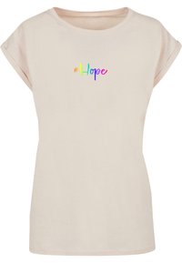 Helles beiges T-Shirt mit kurzen Ärmeln, gefertigt aus weicher Baumwolle. Verfügt über einen bunten "#Hope"-Grafikdruck auf der Brust, mit einem lässigen Schnitt und Rundhalsausschnitt.