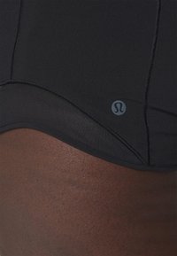 Svarta sportshorts i slät tyg med en nätpanel, platta sömmar och en liten logotyp i nedre kanten.