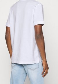 Graues T-Shirt mit kurzen Ärmeln aus Baumwolle, mit lockerer Passform, seitlichen Schlitzen und einem schlichten Design ohne sichtbare Muster oder Logos.