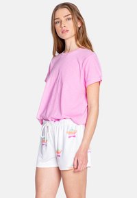 Camiseta de manga corta rosa combinada con pantalones cortos blancos que presentan un patrón colorido de estrellas. Tejido suave, corte holgado y cinturilla elástica en los pantalones cortos.
