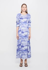 Long blue maxi dress with abstract light blue cloud patterns. Features long sleeves and a fitted bodice, made from smooth fabric.