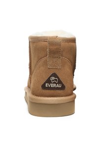 Braune Wildleder-Ankle Boots mit einer weichen Innenauskleidung, die ein dreieckiges Logo-Patch mit der Aufschrift "EVERAU" auf der Rückseite aufweist. Flache Gummisohle.