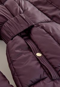 Puffjakke i dyb burgunder med glat tekstur, med en samlet talje og guldhardware-knap på den forreste lynlås.