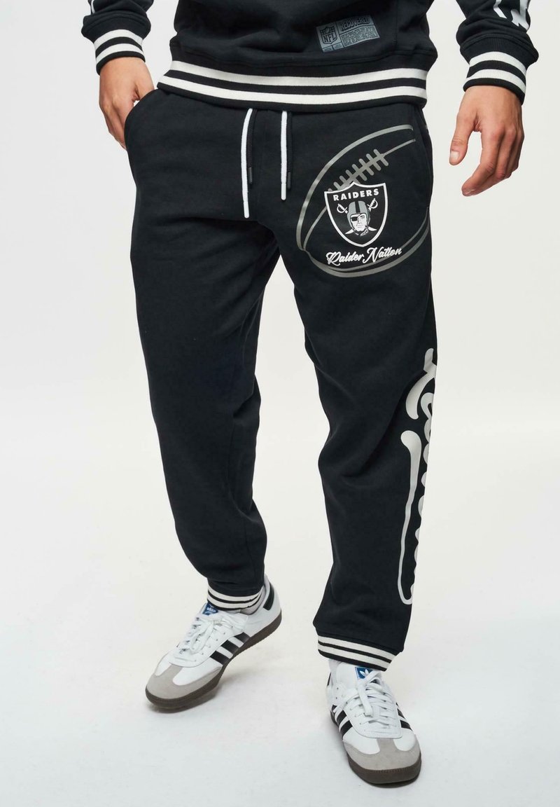 Zwarte sweatpants met een voetbalafbeelding en het "Raiders" logo. Voorzien van witte accenten, een verstelbare tailleband met koord en zijzakken.