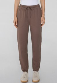 Braune Sweatpants aus weichem Stoff mit einem elastischen Taillenbund und Kordelzug, schmal zulaufenden Beinen und elastischen Bündchen.