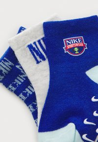 Blaue und weiße Nike-Socken mit einem Logo-Abzeichen, strukturierten Mustern und einem Farbblockdesign mit kontrastierenden Akzenten.