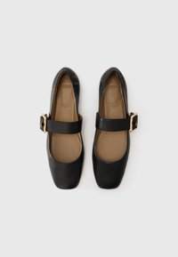 Black leather Mary Jane shoes with a square toe and a wide strap featuring a gold-tone buckle. Soft, tan inner lining.