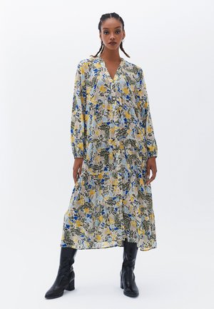 Robe midi à fleurs avec un décolleté en V, des manches longues et une coupe ample. Les couleurs incluent le jaune, le bleu et le vert sur un fond clair.