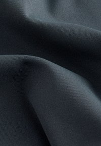 Črna tkanina z gladko teksturo, ki ima subtilen žebljičast vzorec. Material je videti trpežen in prilagodljiv, nežno pada v gubah.