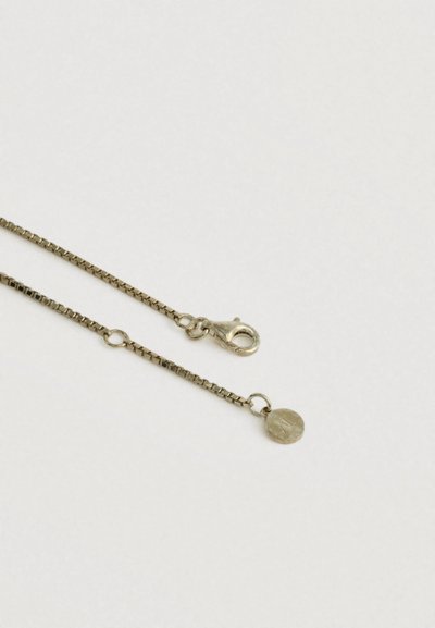 Naszyjnik z łańcuszkiem w kształcie pudełka w złotym odcieniu, z zapięciem typu karabińczyk i małym okrągłym charmem na białym tle.