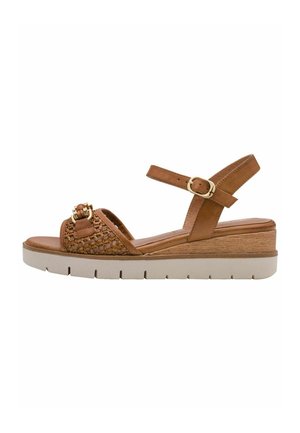 Hnědá klínová sandála s opleteným předním páskem, zlatou přezkou, kotníkovým páskem s přezkou a bílou gumovou podrážkou.