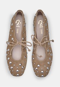 Ballerine in suede marrone con borchie rotonde argentate, lacci alla caviglia e punta arrotondata. Interno imbottito per il massimo comfort.