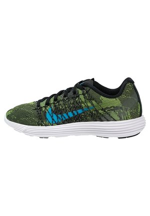 Grüner und schwarzer Sportschuh mit blauem Logo, schwarzen Schnürsenkeln und weißer gepolsterter Sohle, seitlich auf weißem Hintergrund gezeigt.