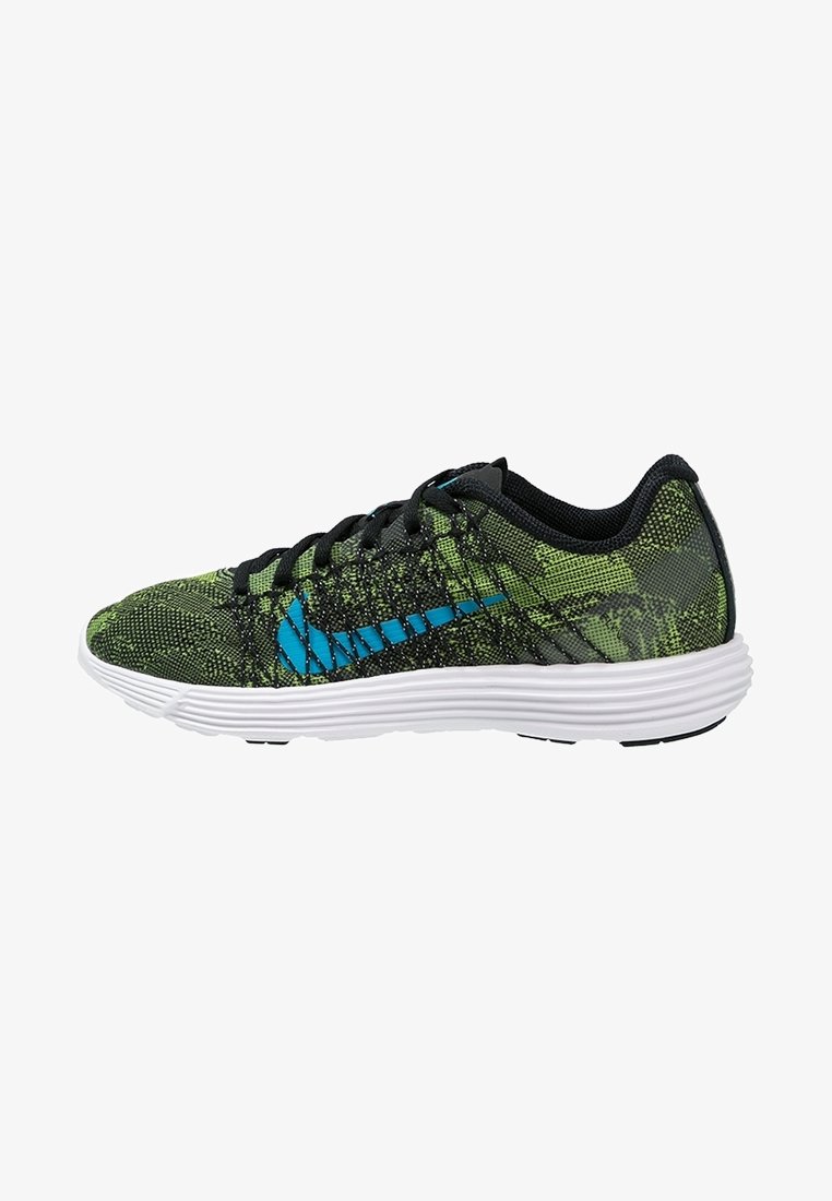 Chaussure de sport verte et noire à motif avec logo bleu, lacets noirs et semelle blanche amortissante, vue de côté sur fond blanc.