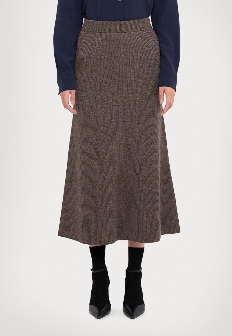 Brun ribbet strik midi-skjørt med en tætsiddende talje. Parret med sorte ankelstøvler og strømper, har designet en flydende silhuet.