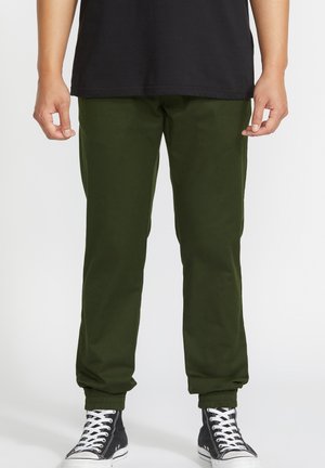 Groene joggingbroek van zachte stof, met ribgebreide boorden, zijzakken en een losse pasvorm, gecombineerd met zwarte high-top sneakers.