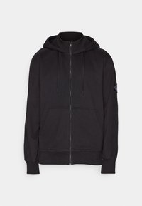 Sudadera con cremallera negra, hecha de un tejido suave, que cuenta con capucha, bolsillos frontales, puños de canalé y un pequeño parche con el logo en la manga izquierda.