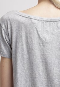 Gray short-sleeve T-shirt made of soft fabric, featuring a wide neckline and a subtle seam detail at the back.