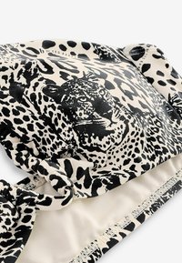 Sutien de bikini cu imprimeu de leopard, realizat dintr-un material negru și crem, cu curele laterale. Textură netedă, cu modele contrastante și un finisaj moale.