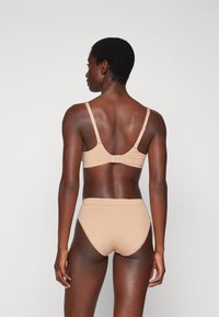 Naaktkleurige beha en set met hoge taille slip, gemaakt van een zachte stof. Beha heeft verstelbare bandjes en een haaksluiting aan de achterkant.