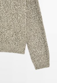 Gebreide trui in lichtgrijze en beige tinten, met een textuurpatroon en ribbelmanchetten. Zacht materiaal en casual ontwerp.