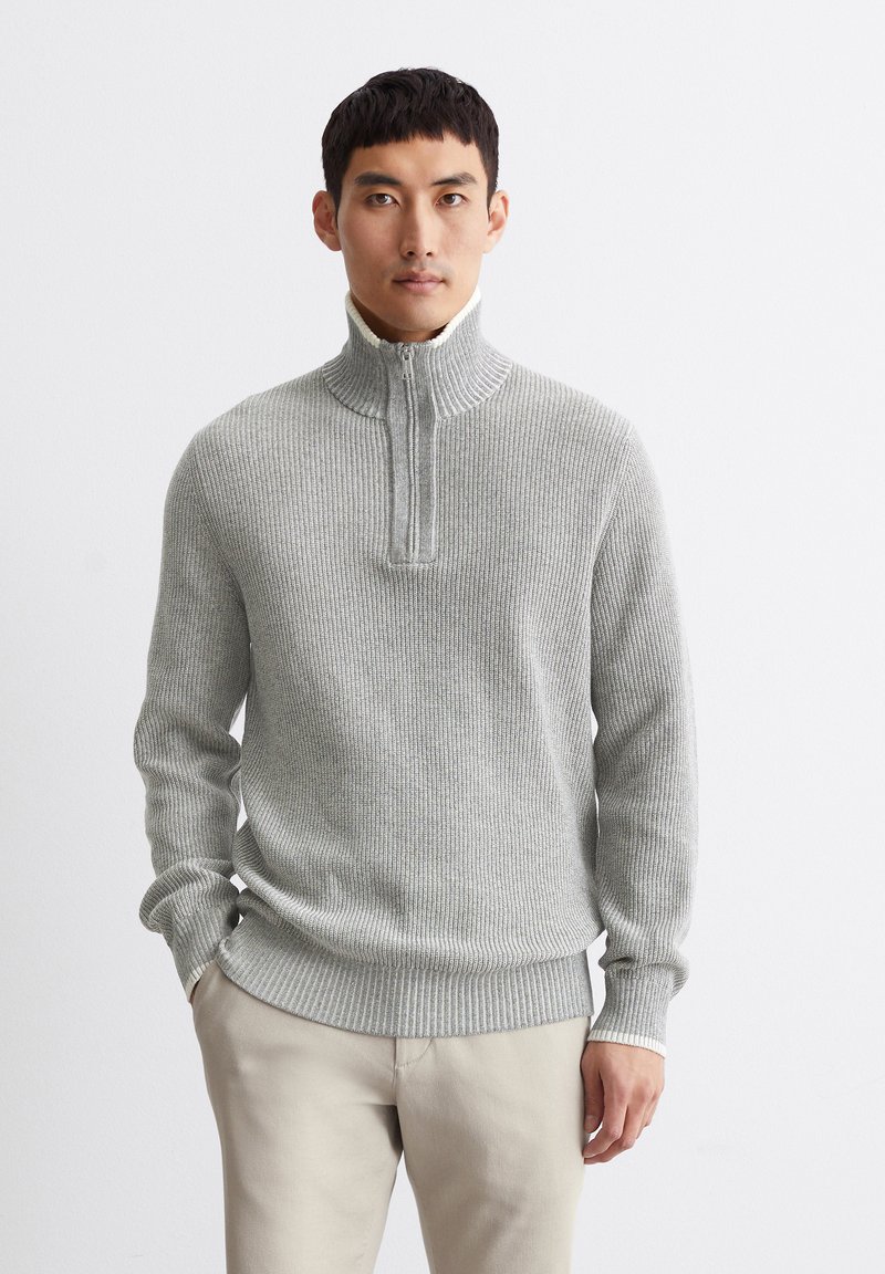 Gray ribbed sweater with a half-zip collar, featuring a textured knit pattern and contrasting inner collar. Paired with light beige pants.