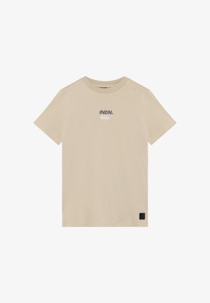 Camiseta beige de algodón con mangas cortas, cuello redondo y texto impreso "INDN." en gris; cuenta con una pequeña etiqueta negra de la marca en el dobladillo.