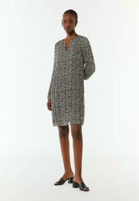 Leopardenmusterkleid aus leichtem Stoff, mit V-Ausschnitt, langen Ärmeln und lockerer Passform, kombiniert mit schwarzen, hohen Mules.