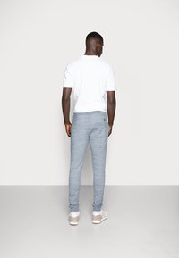 Camiseta blanca de manga corta combinada con joggers gris claro. Los joggers presentan un patrón texturizado, cinturilla elástica y puños ajustados.