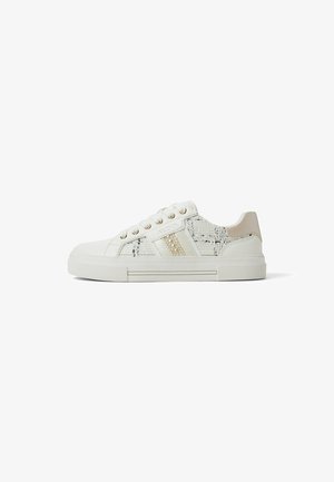 White sneakers with a textured fabric upper, gold eyelets, and a smooth beige heel accent. Features a patterned side panel and rubber sole.