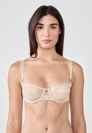 Soutien-gorge beige clair avec délicate broderie dorée, tissu transparent, bords festonnés et accessoires dorés. Doté de fines bretelles réglables.