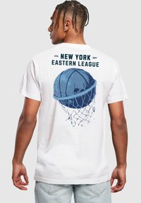 Valge t-särk, millel on sinine korvpalligraafika ja tekst "NEW YORK EASTERN LEAGUE" seljal; lühikesed varrukad ja mugav lõige.