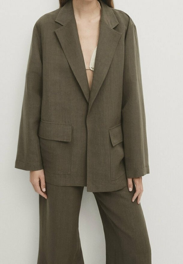 Olijfgroene oversized blazer met notch lapels, twee voorzakken en een gestructureerde vorm, gecombineerd met bijpassende wijde broek.