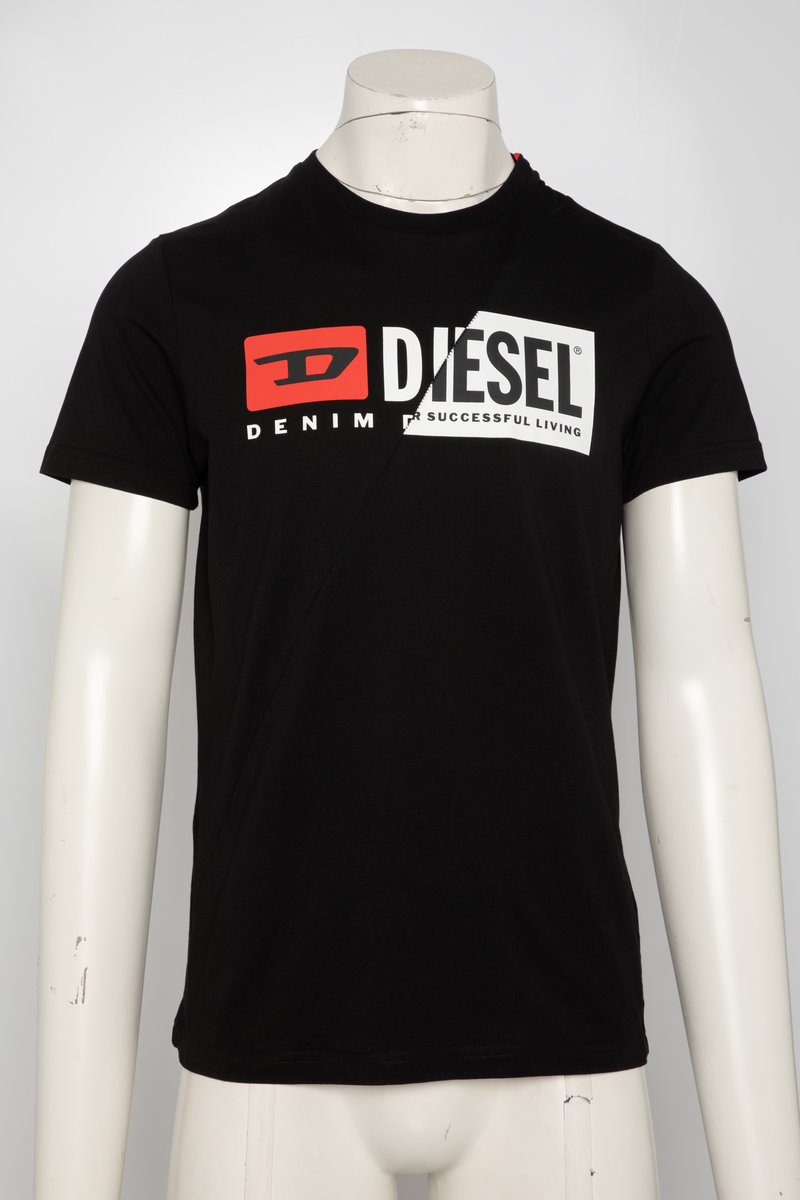 Juoda medvilninė trumpomis rankovėmis marškinėlė. Ant jo yra didelis baltas ir raudonas „DIESEL“ logotipas bei mažas raudonas akcentas ant peties. Klasikinio supirkimo.